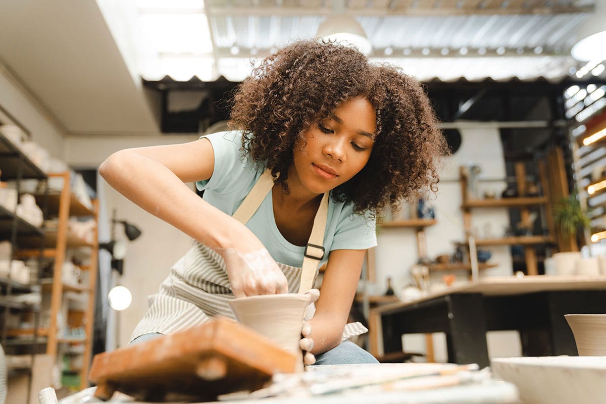 Woman of color making pottery.